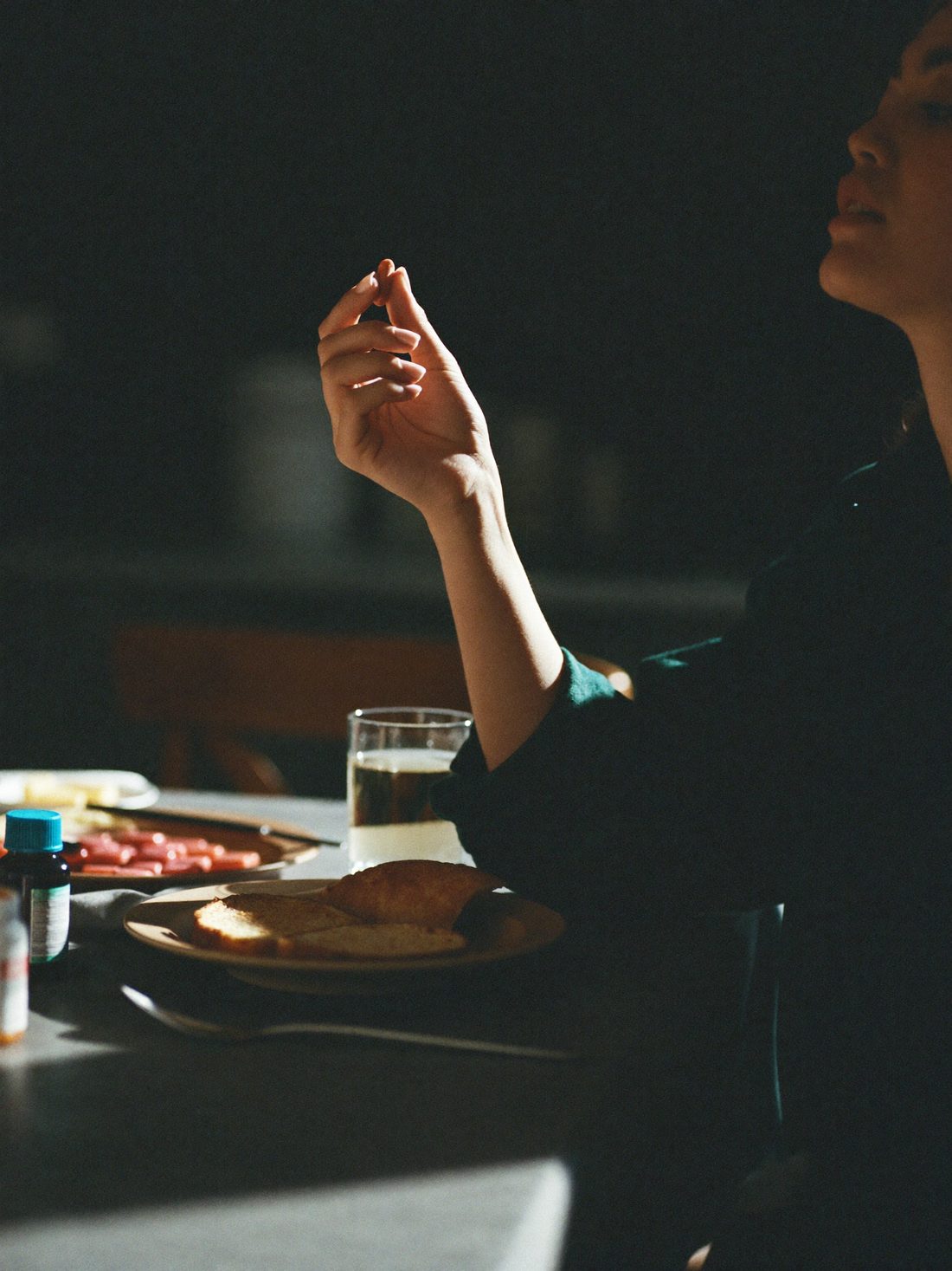 A person pausing with a glass of water and a tablet at a kitchen table